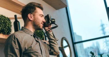 barbat face fotografii cu un aparat foto intr-un apartament