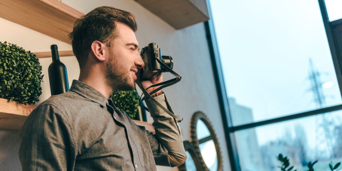 barbat face fotografii cu un aparat foto intr-un apartament