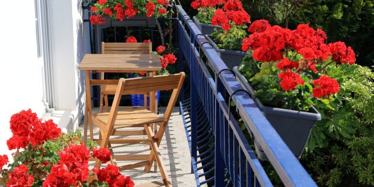 balcon de mici dimensiuni amenajat cu mobilier si flori