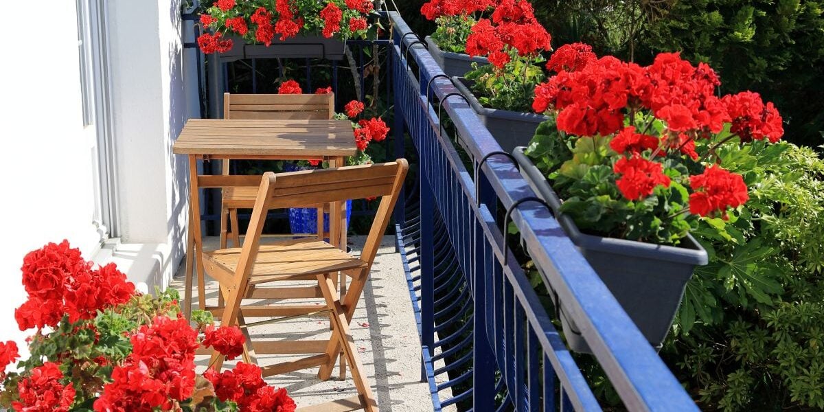 balcon de mici dimensiuni amenajat cu mobilier si flori
