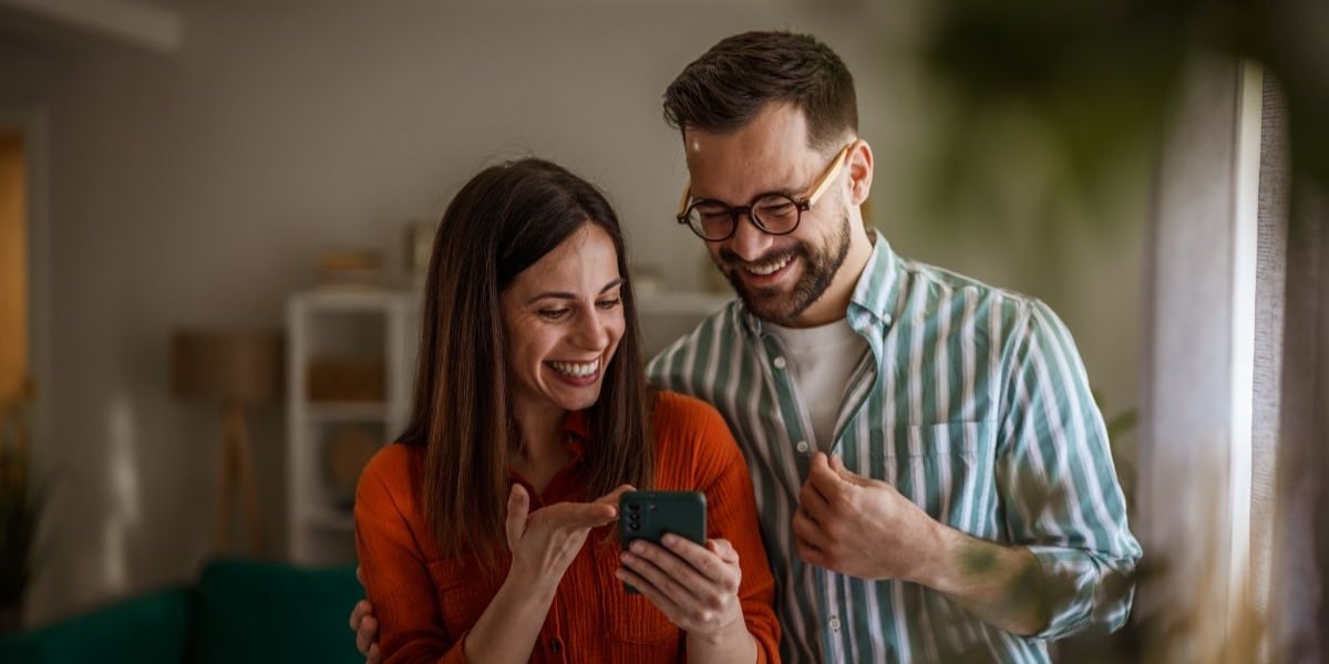 cuplu analizeaza pe telefon oferte de chirii pentru apartamente