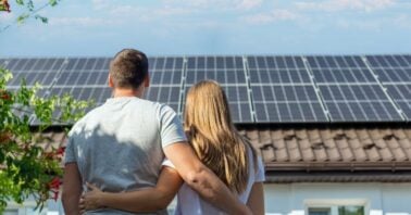 cuplu priveste acoperisul casei pe care sunt montate panouri fotovoltaice