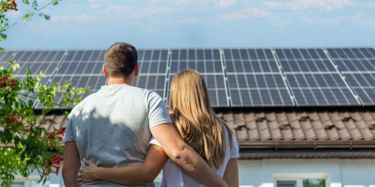 cuplu priveste acoperisul casei pe care sunt montate panouri fotovoltaice