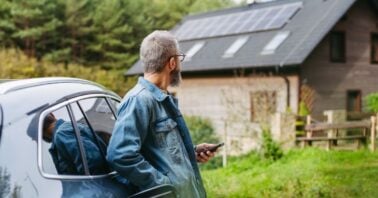 barbat priveste o casa pe care sunt montate panouri fotovoltaice