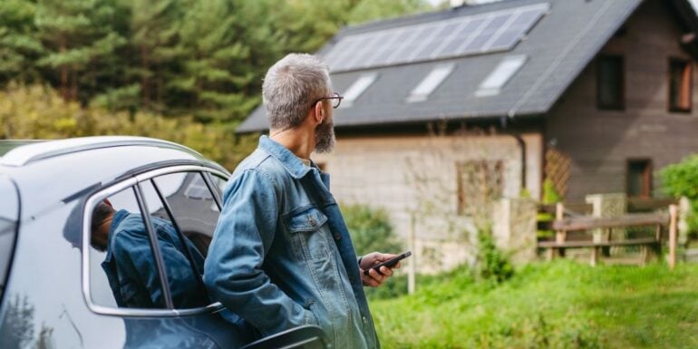 barbat priveste o casa pe care sunt montate panouri fotovoltaice