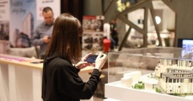 femeie fotografiaza macheta unui ansamblu rezidential la targul imobiliar timisoara